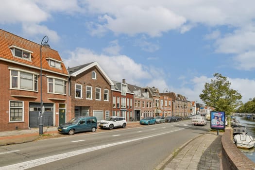 A picturesque street featuring well-preserved historic buildings, parked cars, and lush trees along the waterway. Perfect for urban exploration enthusiasts.