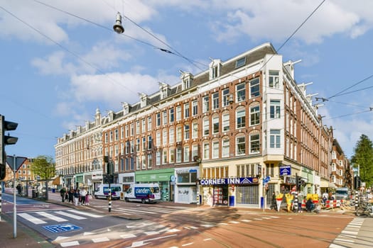 A view of a historic urban building facade on a bustling street showcasing architecture, traffic, and pedestrians, under a clear blue sky.