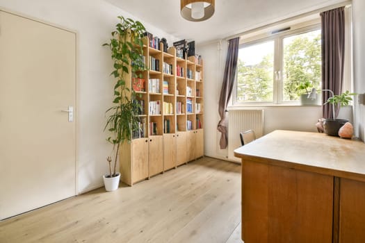 A serene indoor space featuring a wooden shelf filled with books, a cozy table, and a vibrant green plant by a large window inviting natural light.