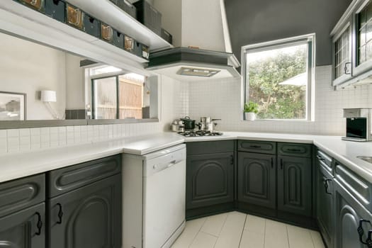 A stylish modern kitchen featuring grey cabinetry, sleek countertops, and natural light streaming through the windows, creating an inviting cooking space.
