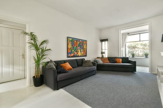 Stylish living room featuring a bright color palette, comfortable sofas, and indoor plants that enhance the ambiance and aesthetics of the space.