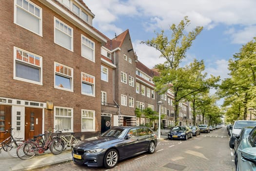 A picturesque urban street lined with trees and parked cars, showcasing a blend of modern and historic architecture in a vibrant neighborhood.