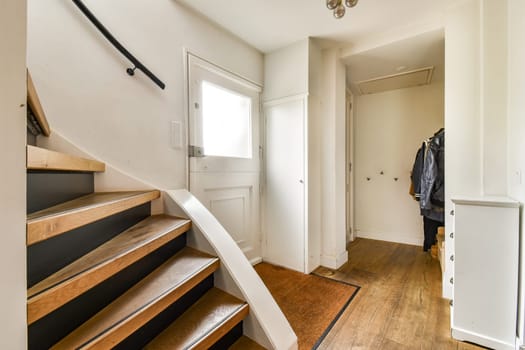 A well-lit indoor space showcasing a contemporary staircase, wooden flooring, and minimalistic decor, creating a sense of elegance and openness.