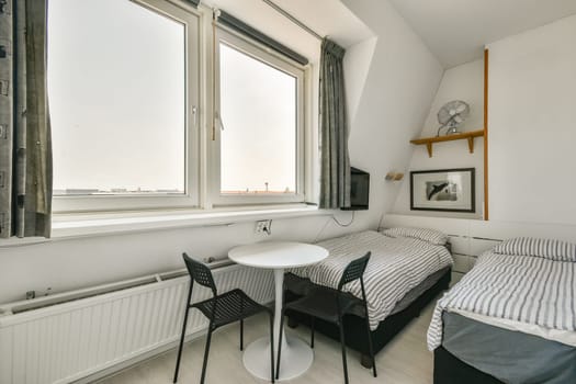 A sleek and modern bedroom design featuring two single beds, a small table, and generous natural light from large windows. The minimalist decor emphasizes simplicity.