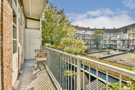 A serene balcony view showcasing lush greenery and cozy seating, framed by charming buildings in a peaceful urban courtyard on a sunny day.