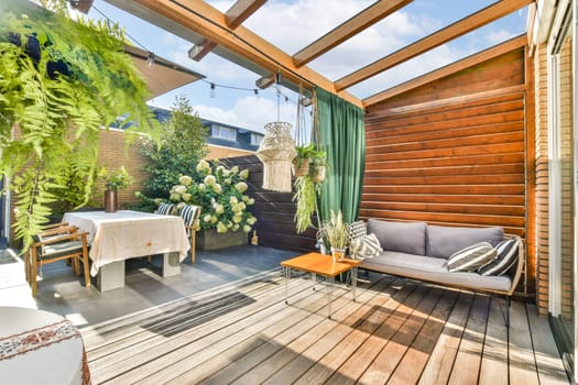 A beautifully designed outdoor patio featuring wooden elements, vibrant greenery, and comfortable seating, perfect for relaxation and entertaining guests.