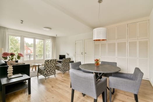 A stylish living room featuring contemporary furniture, large windows allowing natural light, and a chic color palette, creating a comfortable atmosphere.
