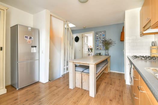 A well-designed kitchen featuring a modern refrigerator, wooden dining table, and bright walls that enhance the airy atmosphere, ideal for family meals.