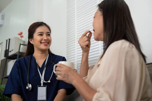 During a home visit, a caregiver smiles at an elderly patient as she assists her with taking medication, enhancing both health and trust.