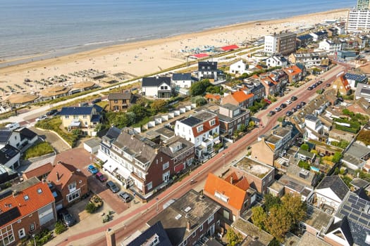 Featuring a charming coastal town, this aerial perspective showcases sandy beaches, residential areas, and vibrant beach activities, perfect for summer visits.