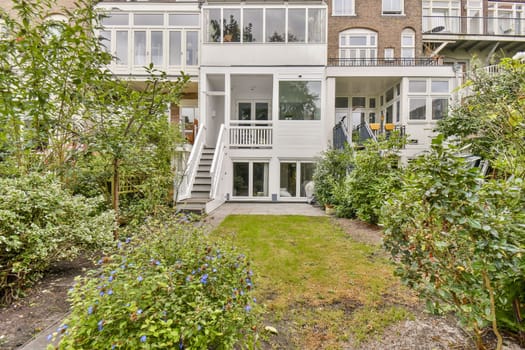 A contemporary home featuring multiple glass windows and an inviting garden area with vibrant greenery and well-maintained landscaping.