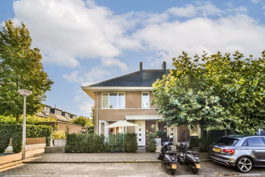 A contemporary home surrounded by vibrant green trees and well-maintained landscaping. Features outdoor elements and a paved driveway.