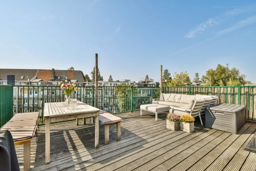 A modern rooftop terrace featuring wooden furniture, vibrant plants, and a scenic view under a clear blue sky, perfect for relaxation and social gatherings.