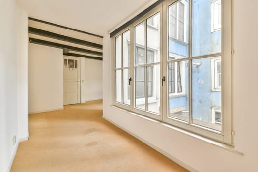Bright interior space featuring expansive windows that allow natural light, complemented by soft texture flooring and a minimalist design.