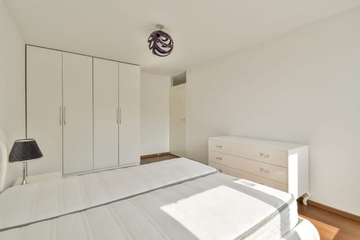 A contemporary bedroom featuring a simple design with a bed, wardrobe, and nightstand, highlighting neutral colors and clean lines for a serene atmosphere.