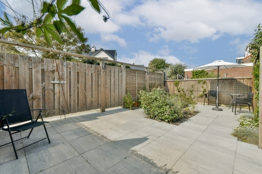 A tranquil outdoor patio featuring wooden fencing, stone flooring, and lush plants, perfect for relaxation or social gatherings.