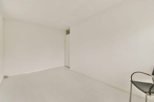 A bright and spacious minimalist room featuring white walls and a simple design. The floor is light-colored, and the furnishings are minimal, enhancing the open feel.