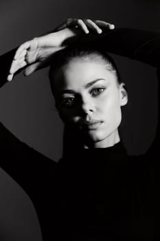 Stunning portrait of a woman with a strong expression, arms raised, in dramatic black and white lighting. A perfect representation of confidence and elegance.