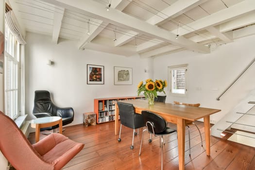 A well-lit modern interior featuring a wooden table, stylish chairs, and vibrant sunflowers adds freshness to the warm ambiance, showcasing contemporary design elements.