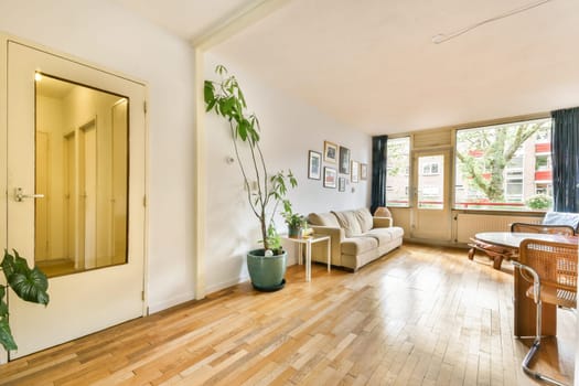 A bright and inviting living room showcasing wooden flooring, a comfortable couch, and decorative plants that enhance the ambiance and give a homey feel.