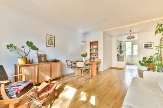 An inviting living area showcasing wooden furniture, plants, and natural light, creating a warm and comfortable atmosphere. Ideal for relaxation and social gatherings.