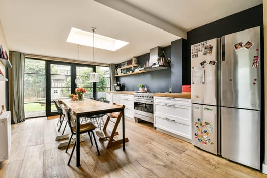 A beautifully designed modern kitchen featuring a spacious layout, large windows for abundant natural light, and contemporary furnishings. Perfect for cooking and entertaining.