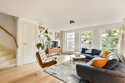 Bright, inviting living room with modern furniture, large windows allowing natural light, and a touch of greenery. Perfect for relaxation and social gatherings.