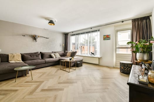 A stylish modern living room featuring a comfortable sofa, elegant decor, and ample natural light from large windows, creating a welcoming ambiance.