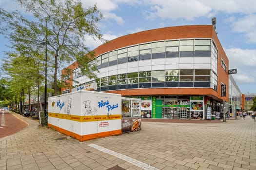 The image showcases a contemporary retail building featuring large windows and vibrant outdoor signage, set amidst lush greenery.