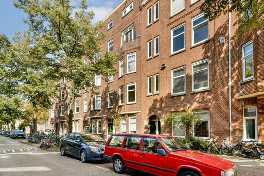 A picturesque urban street scene showcasing brick buildings, greenery, and parked bicycles alongside a classic red car.