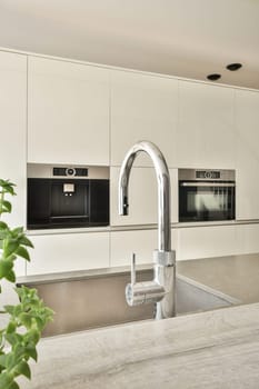 Contemporary kitchen featuring a minimalist design, sleek stainless steel faucet, and elegant cabinetry. A harmonious blend of style and functionality.