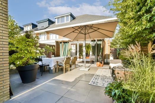 A beautifully arranged outdoor patio featuring comfortable seating, a large umbrella, and lush greenery, perfect for relaxation and gatherings.
