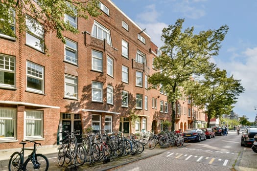 A vibrant street scene featuring red-brick buildings, bicycles neatly parked, and trees lining the sidewalk. The atmosphere is lively and inviting, embodying urban life.