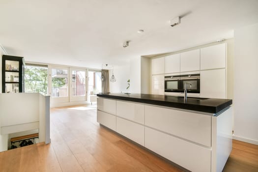 A sleek, modern kitchen featuring light-colored cabinetry and a spacious design illuminated by natural light streaming through large windows.