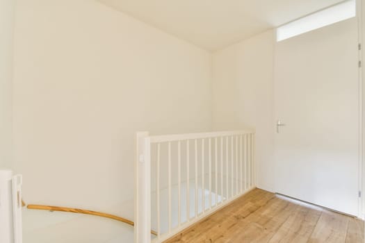 Bright and airy interior featuring a white color scheme with wooden flooring. The space includes a simple railing and a door, ideal for modern living.