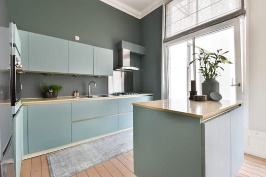 A sleek, modern kitchen featuring a minimalist design with pastel blue cabinetry, wood accents, and plants, creating a harmonious atmosphere.