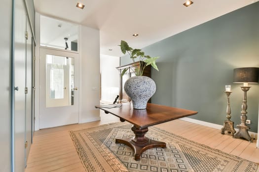 A stylish interior space featuring a wooden table with an elegant decorative vase, complemented by soft lighting and calming wall colors.