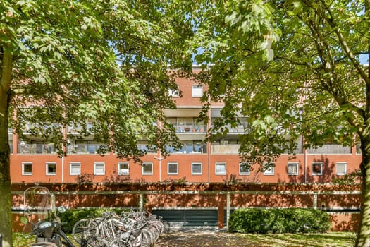 A vibrant urban scene featuring a modern building enveloped in lush greenery, with bicycles parked in front creating a serene atmosphere.