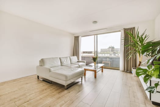 Contemporary minimalist style interior design of light studio apartment with wooden table and chairs in dining zone between open kitchen and living room with white walls and parquet floor