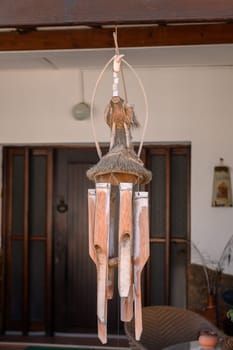 A beautifully crafted bamboo wind chime hangs gracefully from a wooden porch, swaying gently in the warm breeze. Its natural elements resonate harmony and peace, enhancing the serene atmosphere.