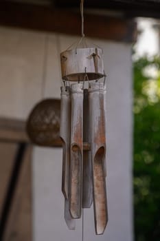 A serene garden features beautifully crafted wind chimes hanging from a wooden structure, reflecting sunlight as they sway softly in the warm seasonal breeze.