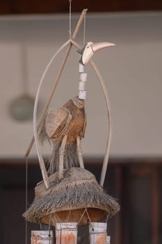 A beautifully crafted bird figure stands elegantly on a thatched platform, highlighting exceptional artistry and attention to detail. Natural materials lend authenticity to this striking decoration.