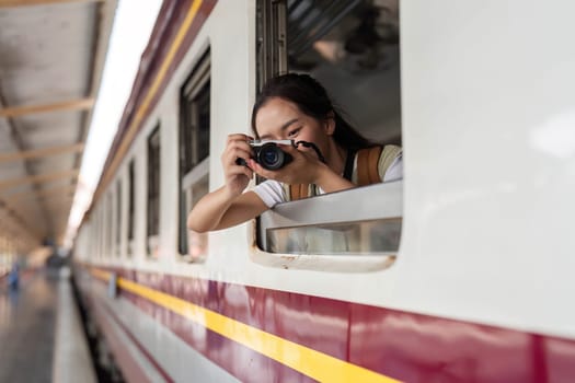 A traveler smiling as she prepares to photograph the scenery outside the train window, ready to document her adventures and experiences.