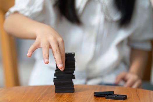 A young girl carefully places game pieces to create a balanced stack, enhancing her problem-solving skills and creativity while playing.