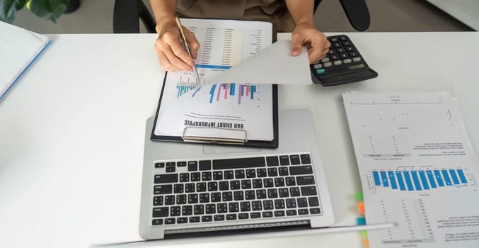 Focused on her work, a professional is engaged in reviewing financial graphs and statistics, ensuring effective documentation practices in a sleek office environment.