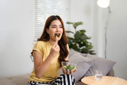 In a serene setting, a woman takes a moment to enjoy her salad, making the most of her morning downtime for self-care and nourishment.
