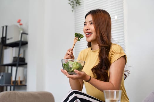 Enjoying a colorful salad at home, this woman embraces her morning routine with joy and vitality, highlighting the importance of healthy eating.