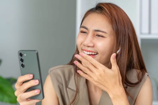A young woman expresses joy as she interacts with friends or family through her smartphone, highlighting happiness and social connection in a modern setting.