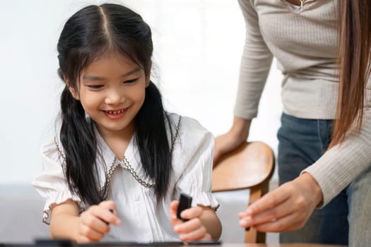 A young girl smiles brightly as she plays a game with her mother, highlighting the importance of family time and simple joys in childhood.
