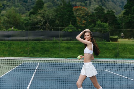 Energetic young woman wearing white sports attire joyfully playing tennis outdoors on a sunny day, promoting a healthy lifestyle and sportsmanship